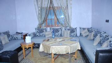 A living room with a sofa, a small table, and a window with curtains.