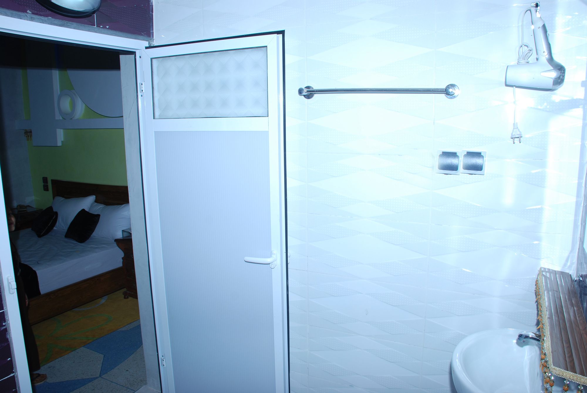 A hotel room with a bed, a bathroom with a sink and mirror, and a door with a handle.