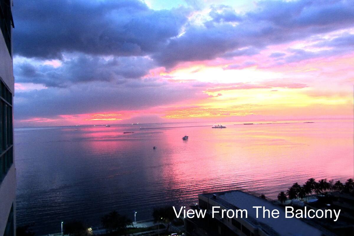 Sonnenuntergangblick von einem Balkon mit Blick auf ein ruhiges Meer und Boote.