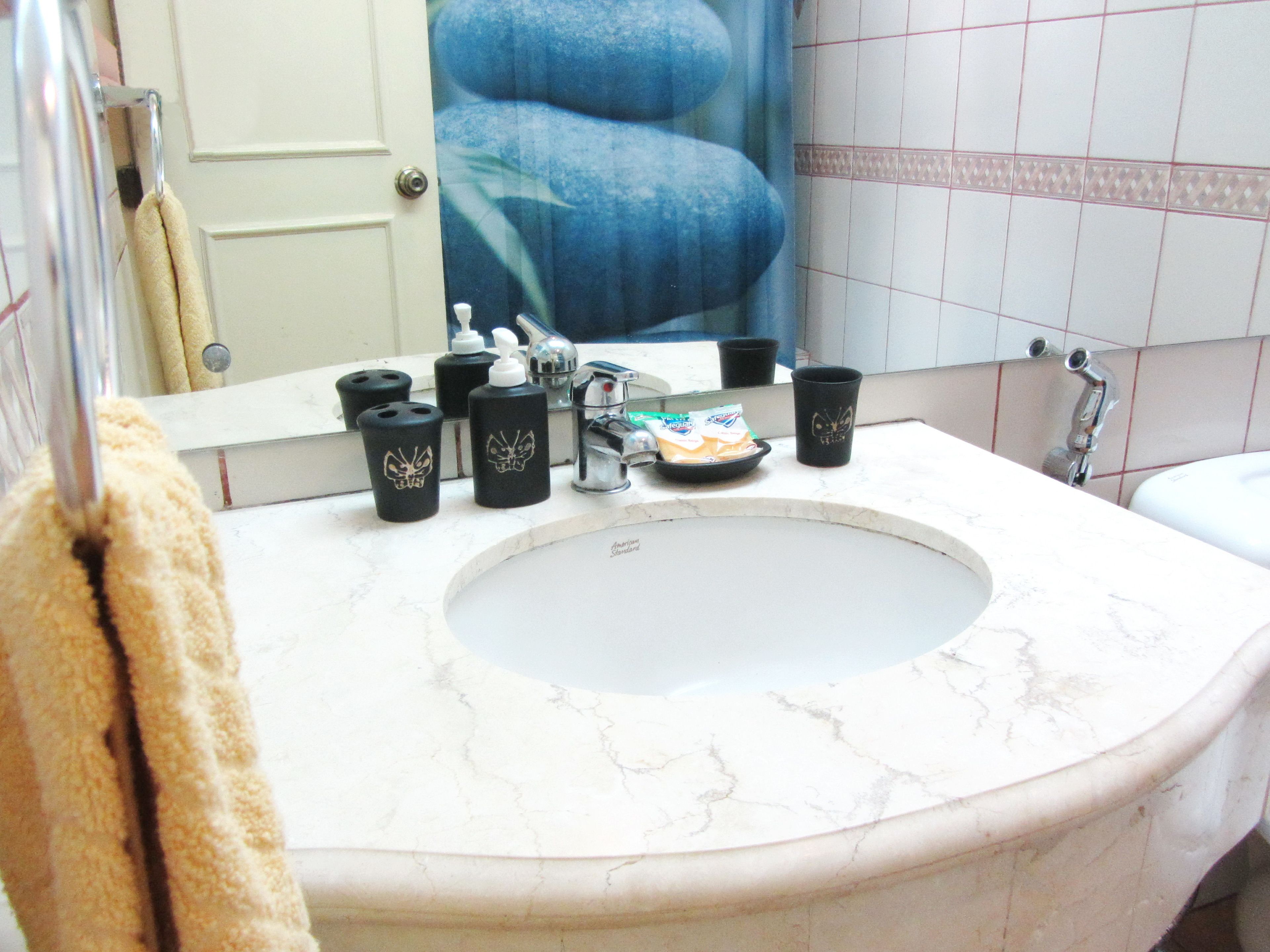 A bathroom with a large sink, a mirror, and toiletries on the counter.