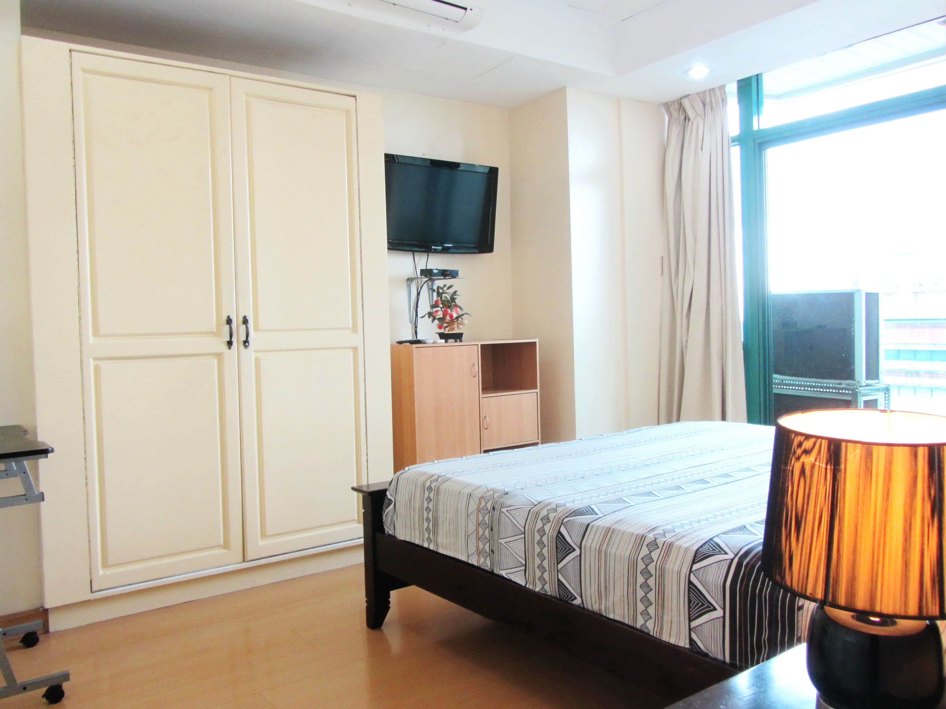 Ein Hotelzimmer mit Bett, Schreibtisch, Fernseher, Kleiderschrank und einem Fenster mit Vorhängen.