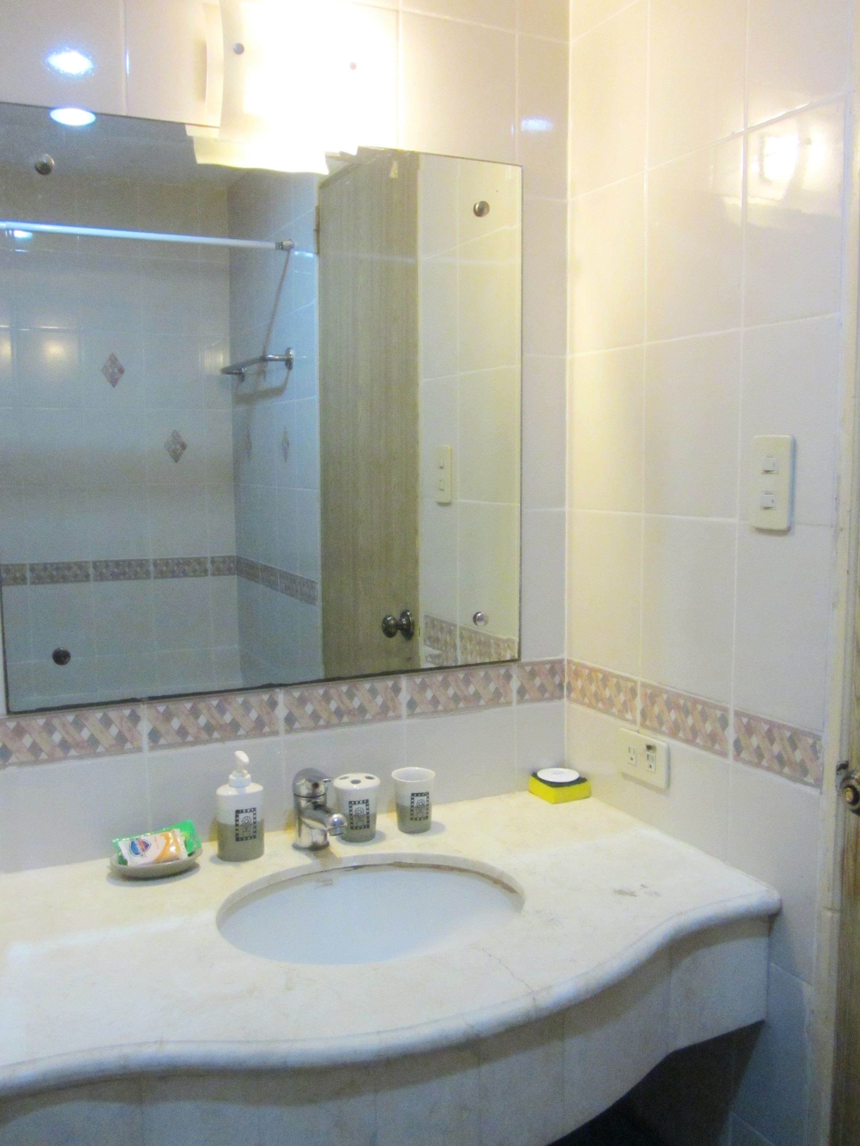 A bathroom with a sink, mirror, and toiletries.