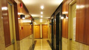 A hallway with marble flooring, wooden doors, and a fire exit sign. - Baywatch Tower (Manila)