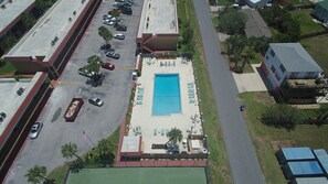 En vy från ovan av ett hotell med en swimmingpool, en parkeringsplats och en väg.