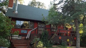 A cabin with a chimney, wooden deck, and a sign welcoming visitors. - Charming log cabin surrounded by the hills of the Cleveland National Forest (Pine Valley)