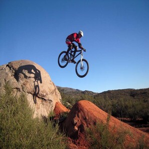 A mountain biker performing a jump over rocks in a natural landscape. - Charming log cabin surrounded by the hills of the Cleveland National Forest (Pine Valley)