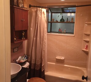 A bathroom with a bathtub, a window with shelves, a toilet, and a vanity with a mirror. - Charming log cabin surrounded by the hills of the Cleveland National Forest (Pine Valley)