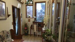 A cozy living room with a wooden sofa, a dining table, and chairs. There are potted plants and a rug on the floor. - Charming log cabin surrounded by the hills of the Cleveland National Forest (Pine Valley)