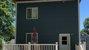 A two-story house with a dark green exterior, white railings, and a small porch area. - 1st Class Rentals Munson Manor IV  at Columbia Street (Oneonta)