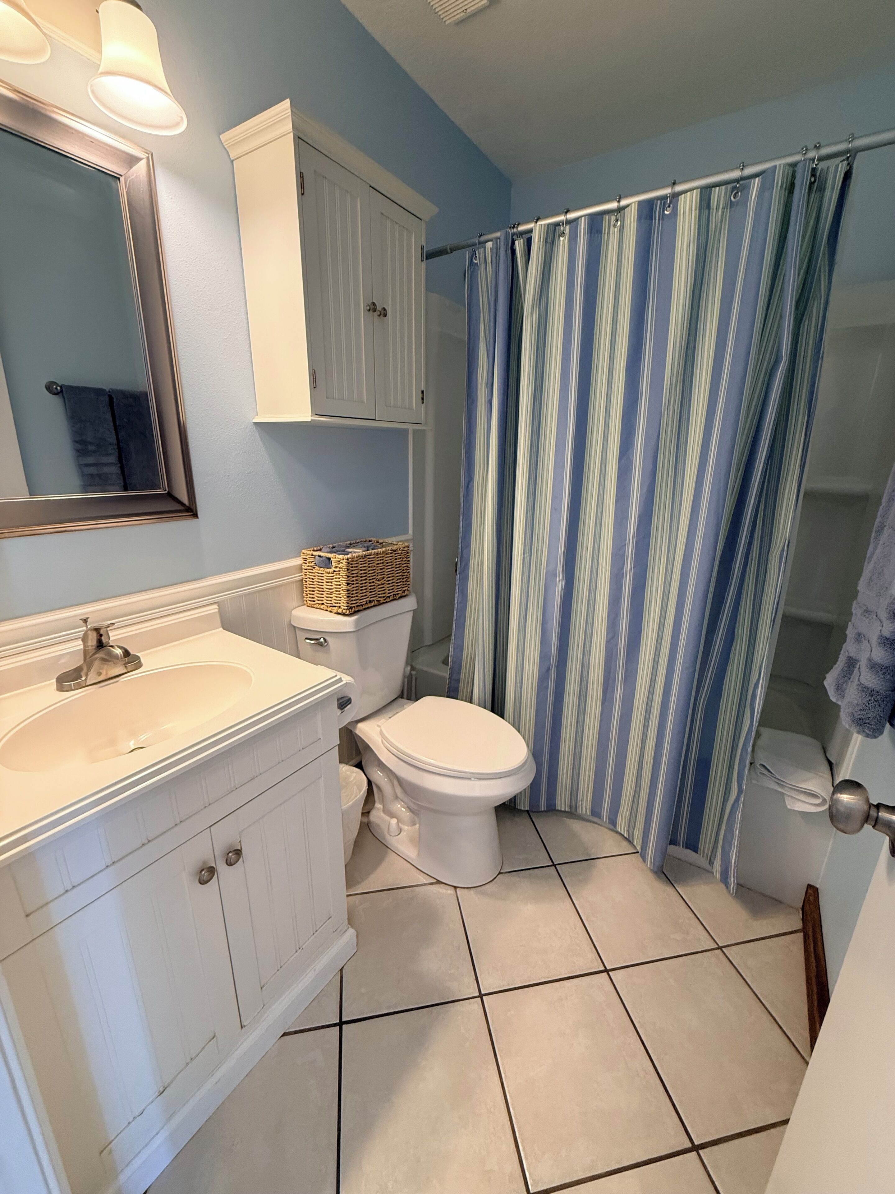 A bathroom with a white sink, a toilet, a mirror, and a shower curtain.