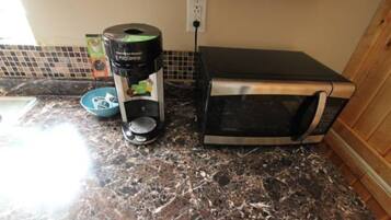 A kitchen with a coffee maker, a toaster, and a microwave on a granite countertop.