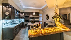 A modern kitchen with dark cabinetry, a marble countertop, and stainless steel appliances. - 5 BDR LUX MODERN BEACHFRONT VILLA PRIVATE INFINITY POOL & OCEAN VIEWS STAFF (Montego Bay)
