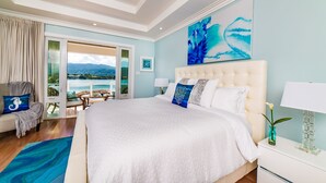 A spacious bedroom with a large bed, a view of a lake, and a balcony with outdoor seating. - 5 BDR LUX MODERN BEACHFRONT VILLA PRIVATE INFINITY POOL & OCEAN VIEWS STAFF (Montego Bay)