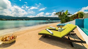 A beachside lounge with a view of the sea and mountains, a pool, and a basket of seashells. - 5 BDR LUX MODERN BEACHFRONT VILLA PRIVATE INFINITY POOL & OCEAN VIEWS STAFF (Montego Bay)