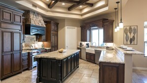 A spacious kitchen with dark wood cabinets, a large island, and a stone fireplace.