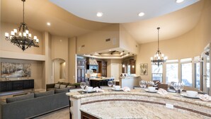 A spacious kitchen with a curved island, dark wood cabinets, and pendant lighting.