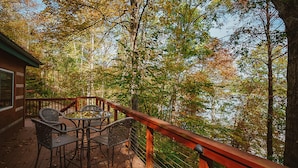 Une terrasse en bois avec une table et des chaises, entourée d’arbres.