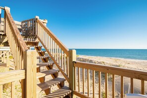 Una escalera de madera que da a una playa, bajo cielos despejados.