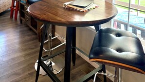 Un comedor con una mesa redonda de madera, sillas de cuero negro y una lámpara colgante.