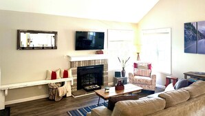 Una sala de estar con chimenea, televisor y sofá.