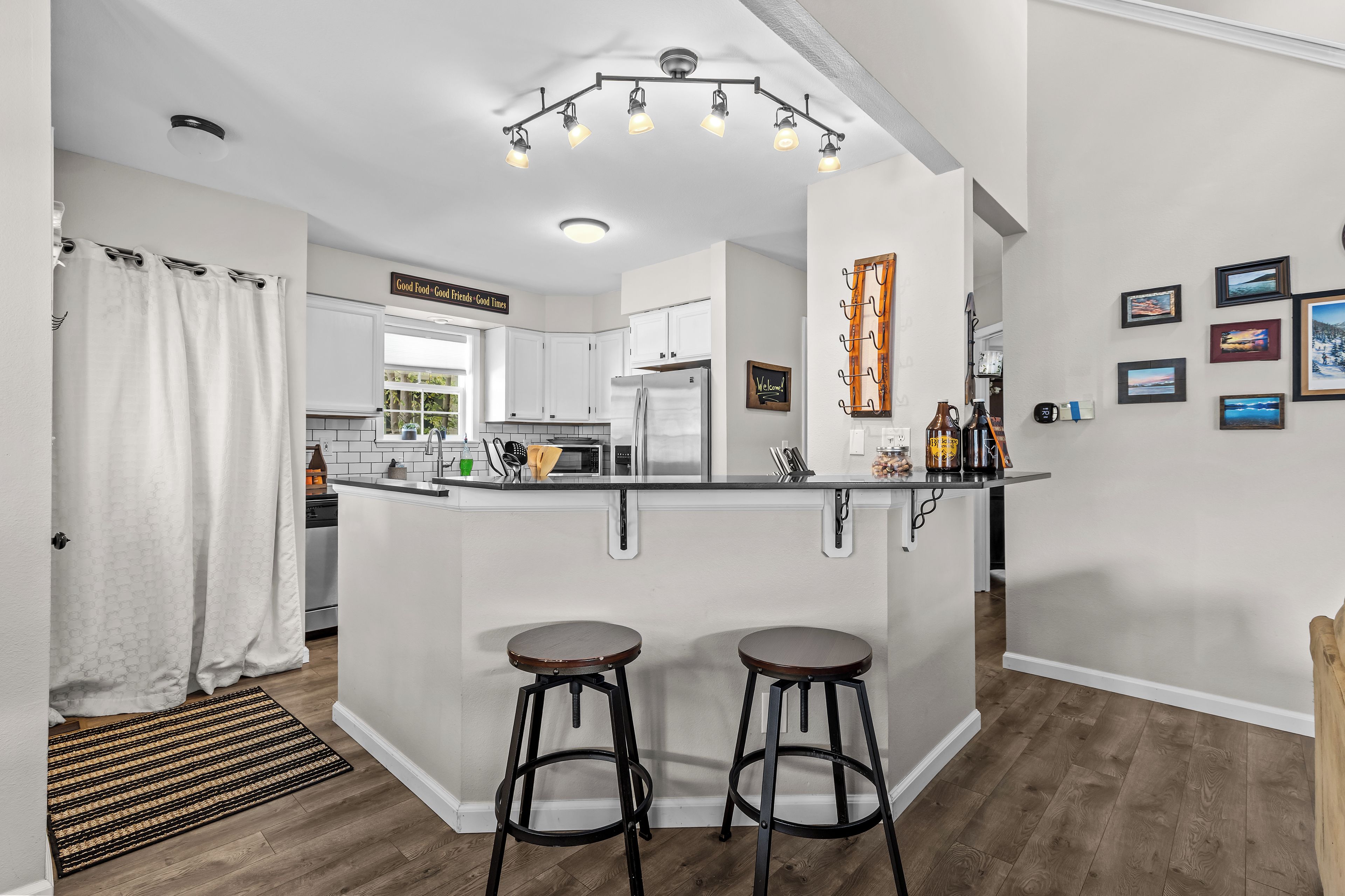Une cuisine moderne avec un îlot central, des tabourets de bar et un luminaire suspendu.
