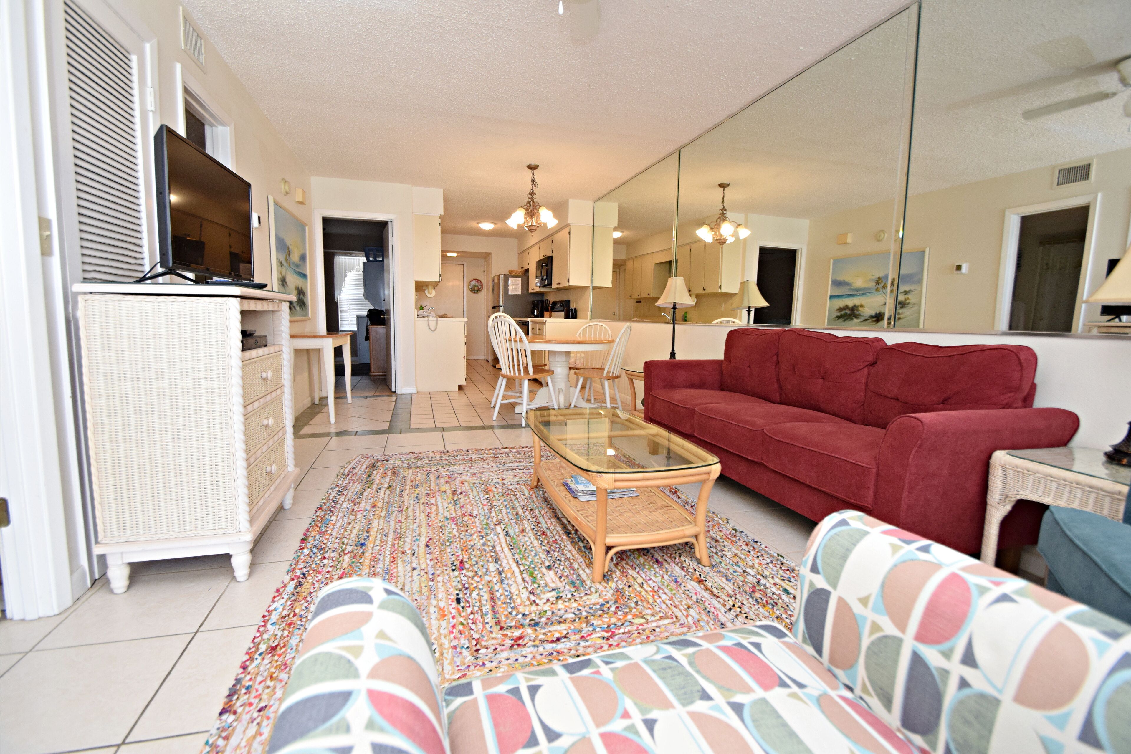 A living room with a red sofa, a glass coffee table, and a patterned rug.