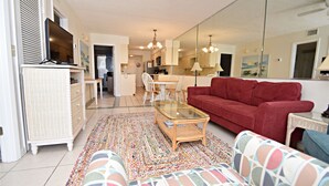 A living room with a red sofa, a glass coffee table, and a patterned rug. - 🌊🎣 Relax and catch a couple fish- Happiness comes in waves. 🎣🌊 (Gulf Shores)