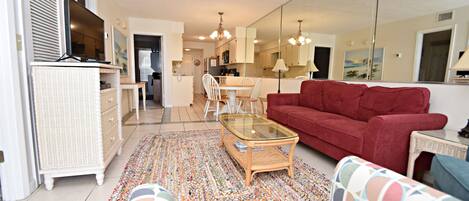 A living room with a red sofa, a glass coffee table, and a patterned rug.