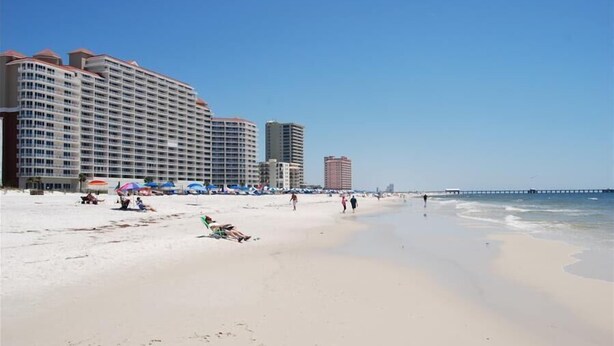 A beach with a large hotel and a pier in the background. - 🌊🎣 Relax and catch a couple fish- Happiness comes in waves. 🎣🌊 (Gulf Shores)
