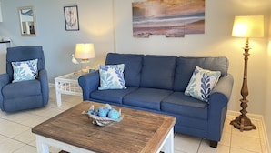 Een woonkamer met een blauwe bank, een bijzettafeltje en een lamp.