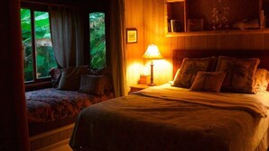 Une chambre confortable avec un lit, une table de chevet avec une lampe et une fenêtre avec des rideaux.