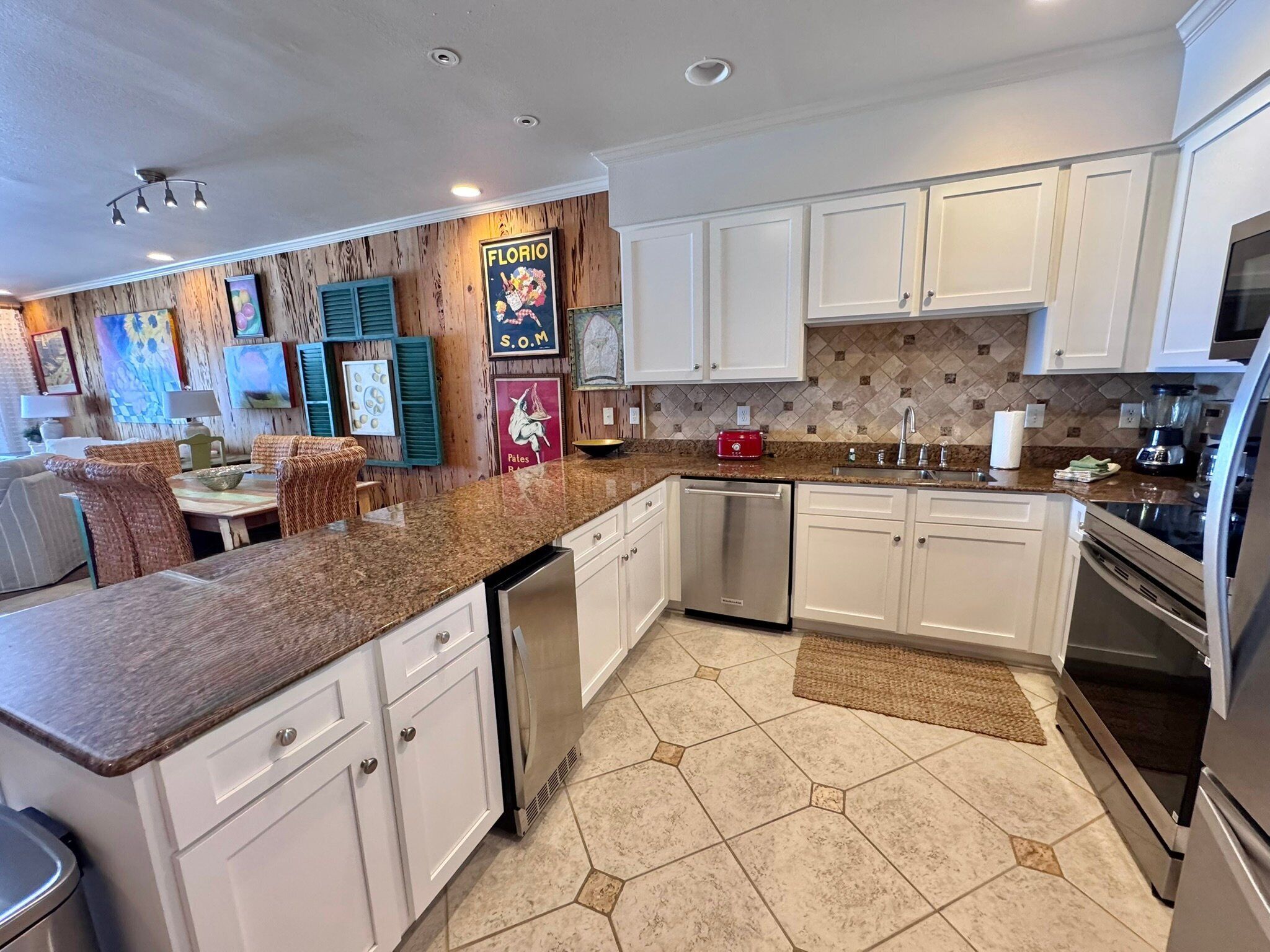 A modern kitchen with white cabinets, granite countertops, and a dishwasher.