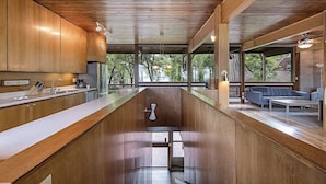 A modern kitchen with wooden cabinets, a central island, and a view of the outdoors. - GLASS HOUSE 5 BR Private Lake Erie Beach Great for Summer, Fall, Winter (Sandusky)