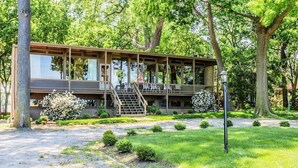 A modern building with a glass facade, outdoor seating, and a staircase leading to the entrance. - GLASS HOUSE 5 BR Private Lake Erie Beach Great for Summer, Fall, Winter (Sandusky)