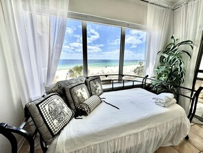 Una camera da letto con un letto, vista sulla spiaggia e una pianta in vaso.