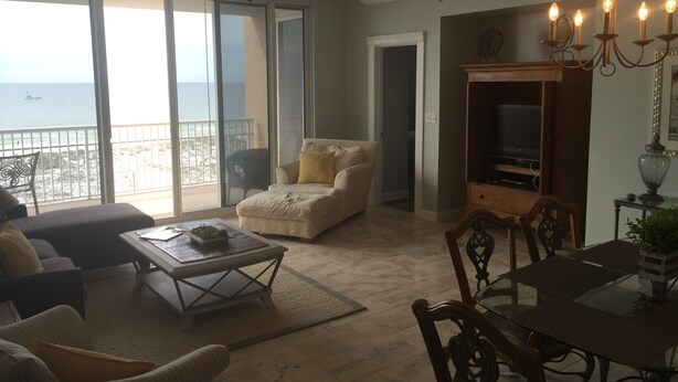 Ein geräumiges Wohnzimmer mit einem großen Schiebeglasfenster, das auf einen Balkon mit Meerblick führt.