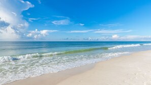 A beach with clear blue water and a sandy shore.