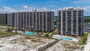 Un hotel di grattacielo con numerosi piani, una piscina e una spiaggia.