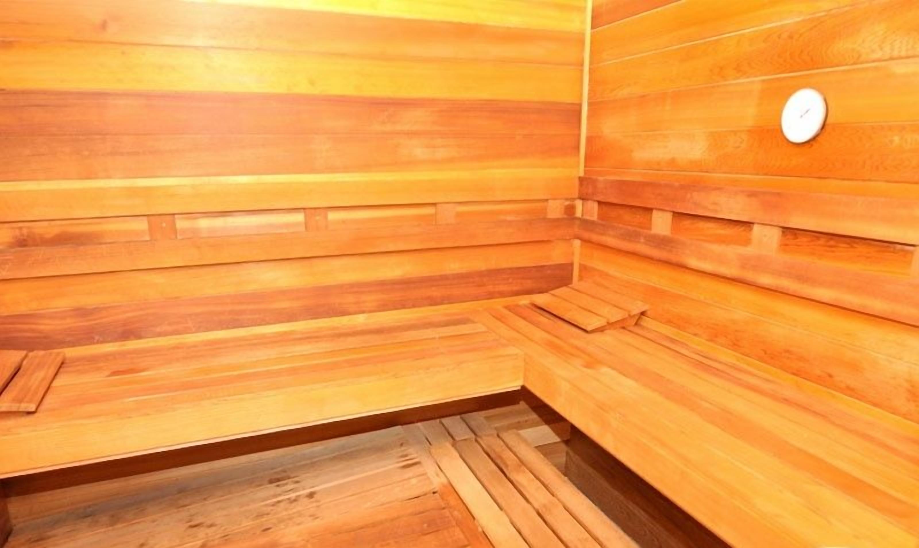 Una sauna de madera con bancos y piso de baldosas.
