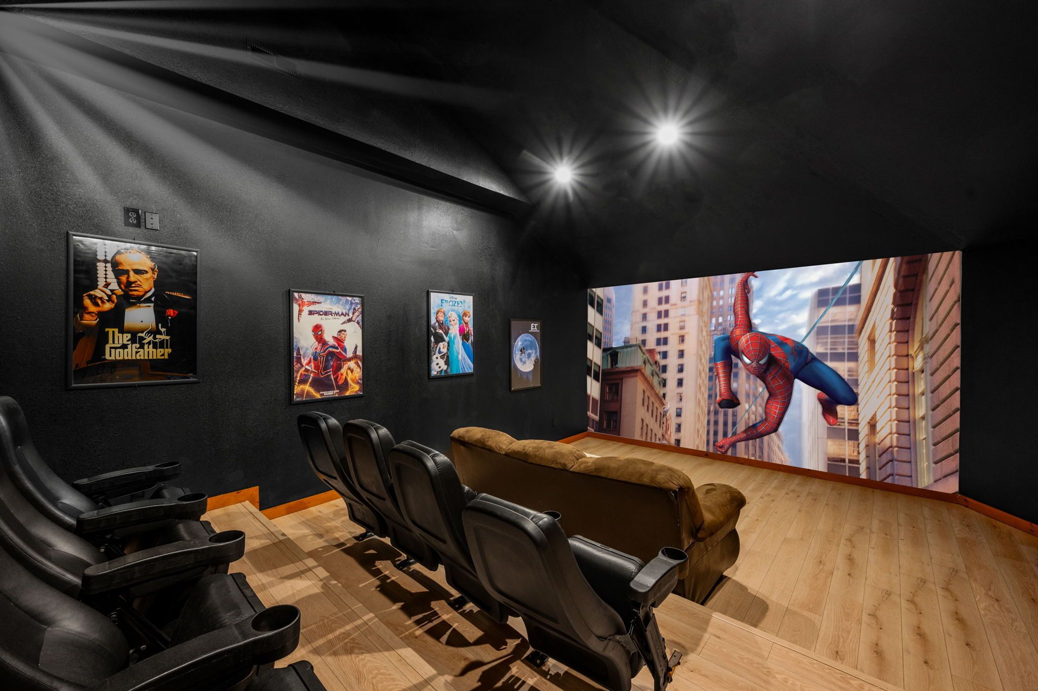 Une salle de cinéma aux murs noirs, ornée d’affiches et d’une grande fresque représentant Spider-Man.