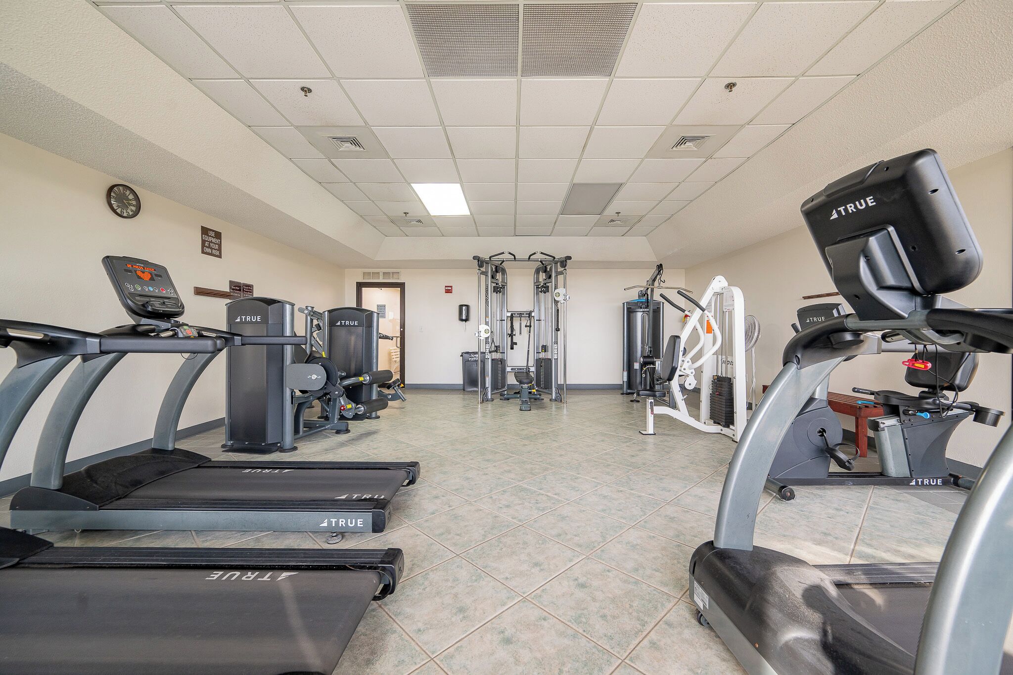 Une salle de sport équipée de tapis de course, d’appareils de musculation et d’un mur recouvert de miroirs.
