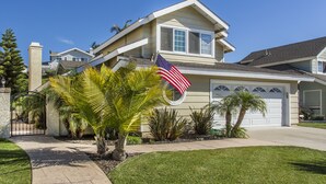 Une maison à deux étages avec un garage, une allée et une pelouse bien entretenue agrémentée de palmiers.