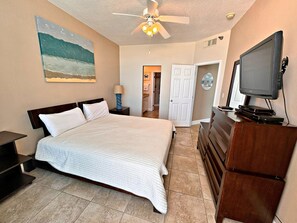 A bedroom with a bed, a TV, a ceiling fan, and a painting on the wall. - The humidity is gone, but the Beach is still here 🌊 Best time of the year! (Gulf Shores)