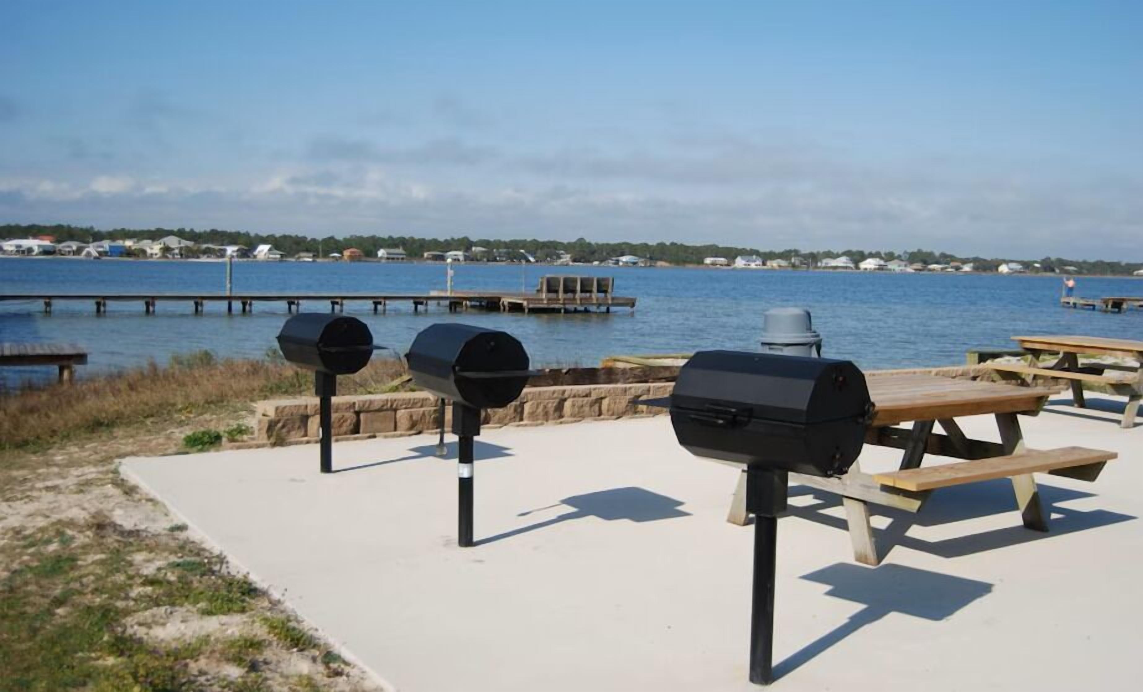 A waterfront picnic area with grills and benches.