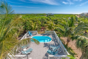 A pool area with a wooden deck, lounge chairs, and a view of the ocean.