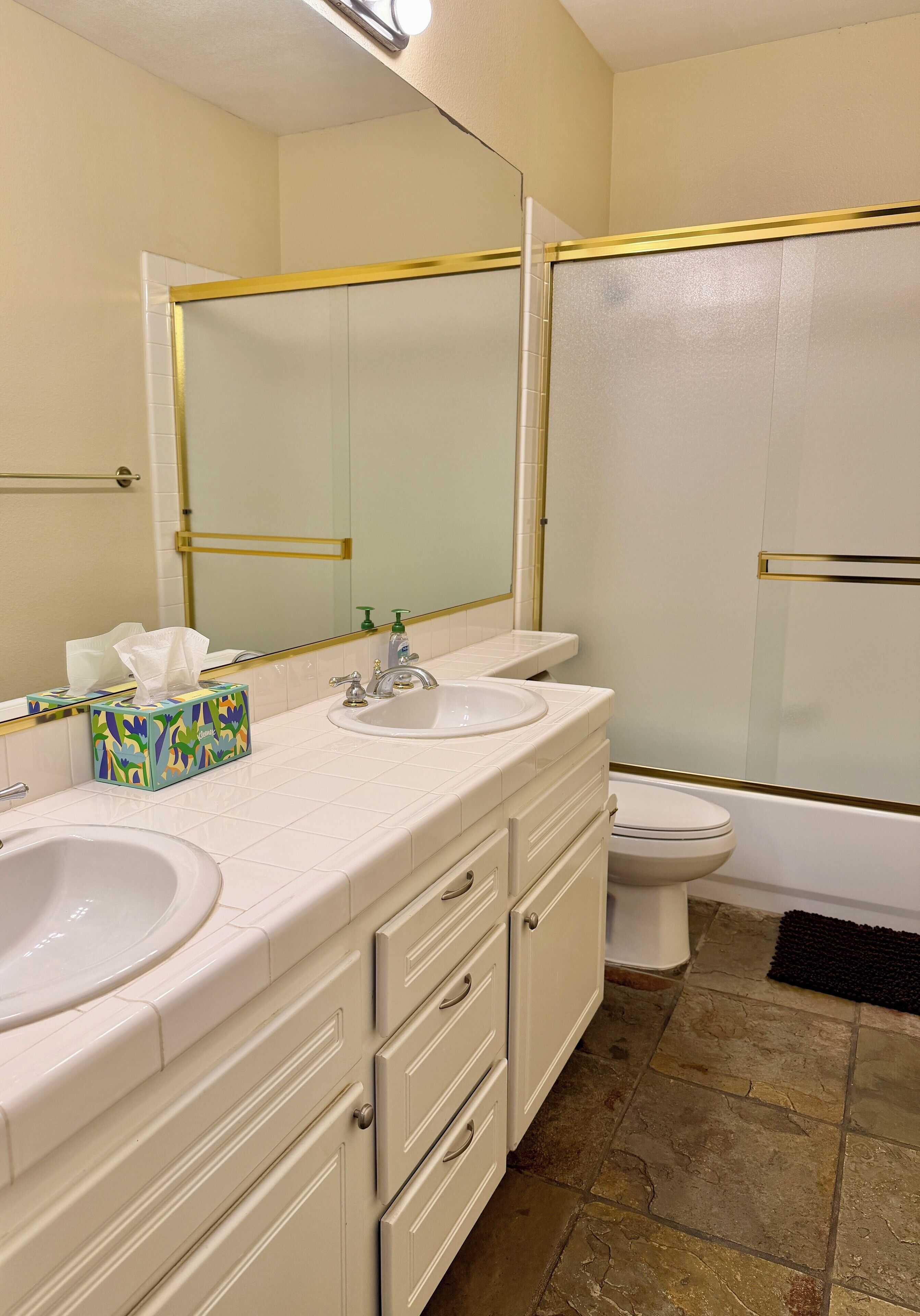 Een badkamer met twee wastafels, toilet en douche.