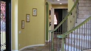Un intérieur spacieux agrémenté d’un escalier en colimaçon, d’un revêtement de sol en pierre et d’une rampe verte.