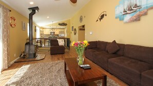 A living room with a brown sofa, a wooden coffee table, a vase with flowers, and a ceiling fan. - Across from Marina, Fishing, Watch the Sea Lions, Great Parking for Boats (Bodega Bay)
