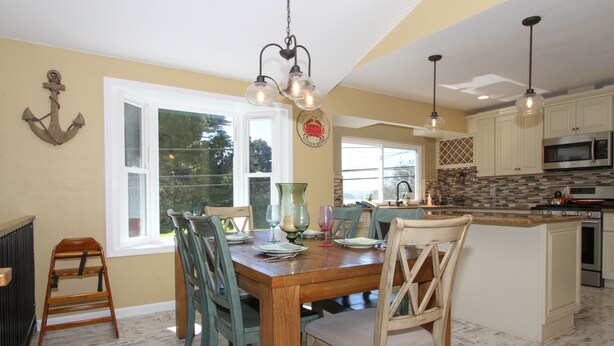 A kitchen with wooden cabinets, a microwave, and a dining area with a wooden table and chairs. - Across from Marina, Fishing, Watch the Sea Lions, Great Parking for Boats (Bodega Bay)