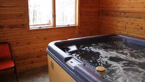 A wooden cabin with a hot tub, a window, and a red chair.